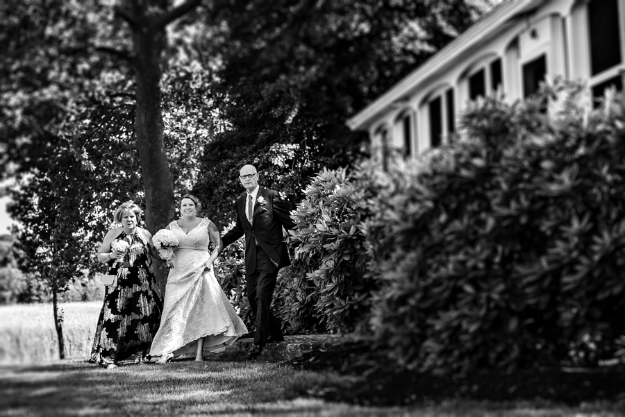 A bride walks with her parents to the wedding ceremony.